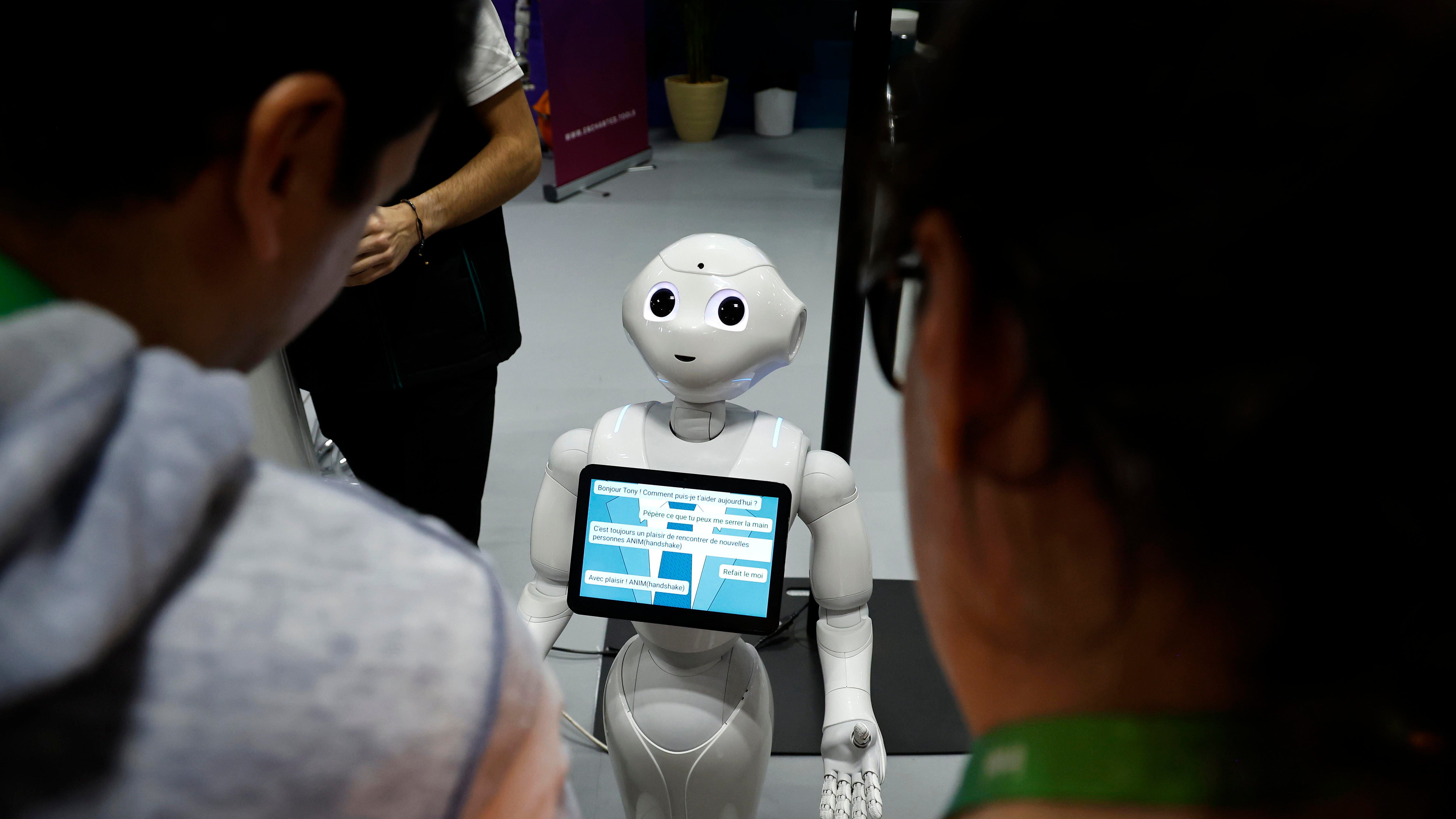 Unos visitantes hablan con el robot 'Pepper' en una imagen de archivo de una feria. EFE/EPA/SEBASTIEN NOGIER