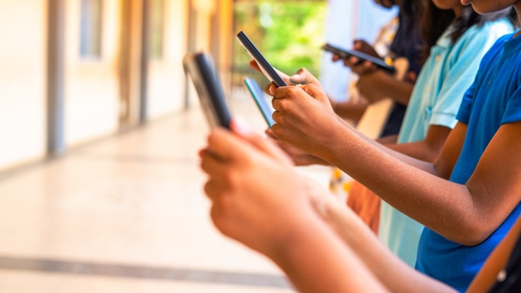 Close up shot, group of children hands busy using smartphone at school corridor - concept of social media, playing games, technology and education