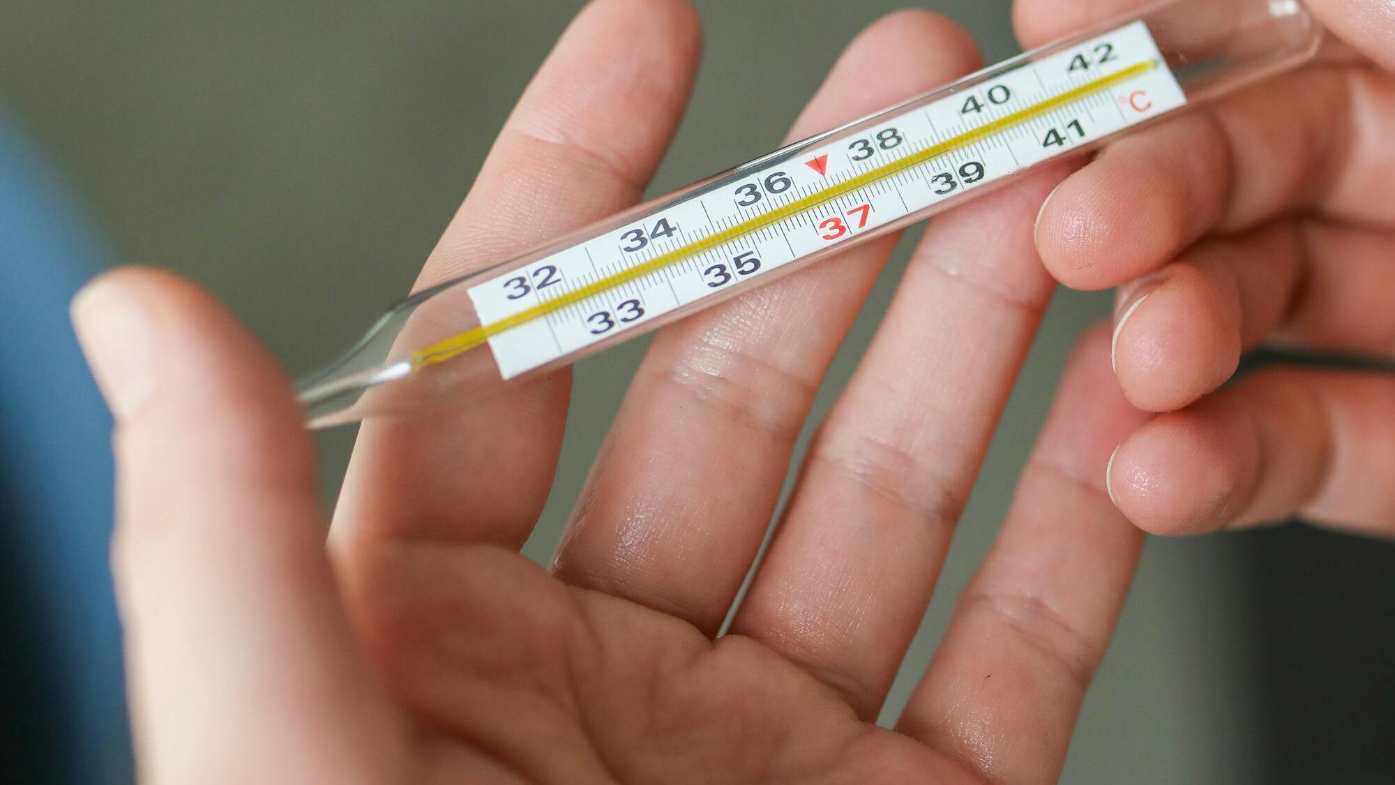 Silhueta de mão segurando termômetro